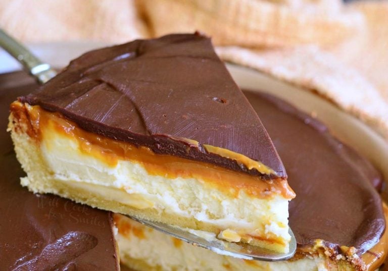 1 slice of cheesecake being held above the rest of the cheesecake pie as viewed close up