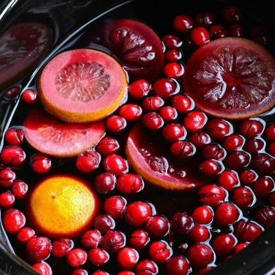 a crock pot shown cooking spiced orange cranberry sangria