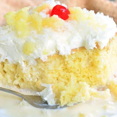 decorative plate with a slice of pina colada tres leches cake with a fork on the plate next to the slice