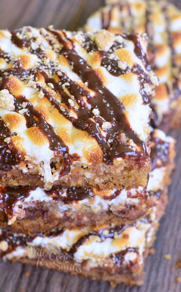 3 layered double chocolate S'Mores crumble cookie bars stacked on top of each other on a dark wooden table as viewed from above