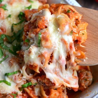 chicken and sausage tortellini casserole in a white decorative baking dish on a wooden table as viewed from above and close up