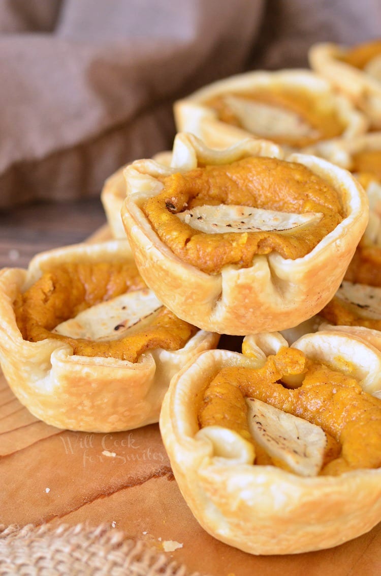 8 mini pumpkin cheesecake pie on a wooden table.