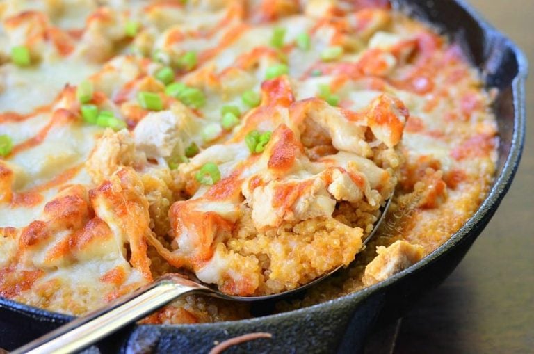 Black skillet filled with creamy siracha chicken and quinoa bake on a wooden table