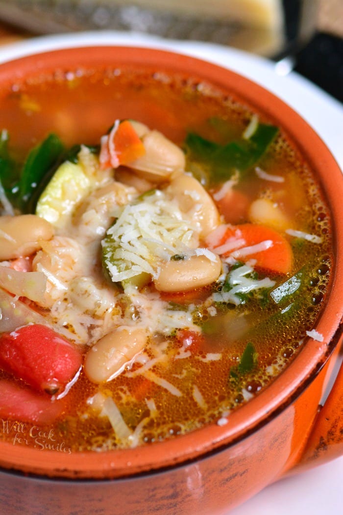 top view of minestrone soup in a red bowl.