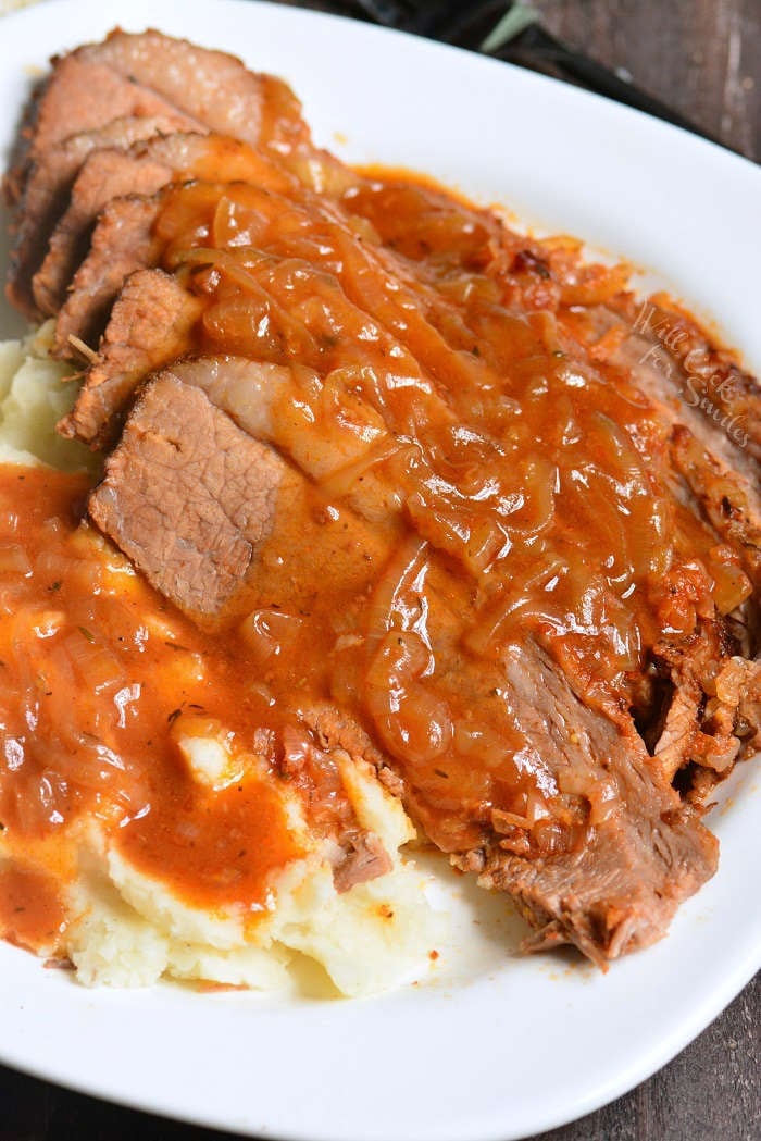 cooked beef brisket on a serving platter with mashed potatoes 