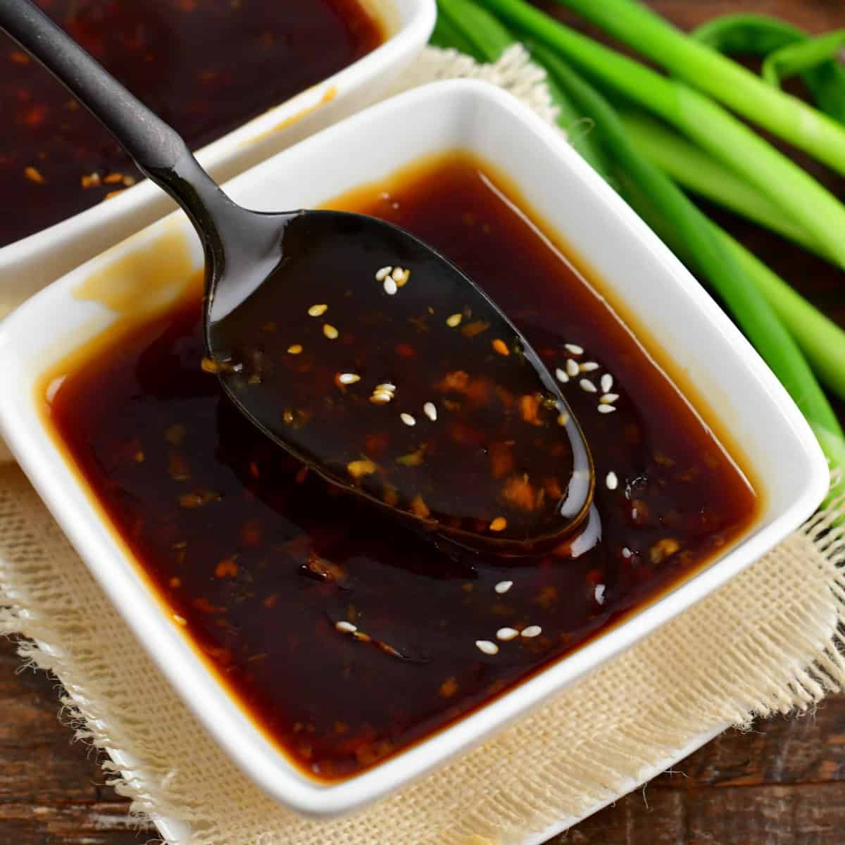 spooning out some homemade teriyaki sauce from the white bowl.