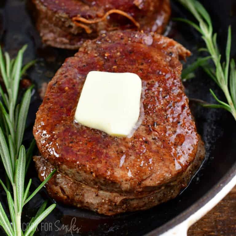 one cooked filet mignon in the skillet topped with butter.