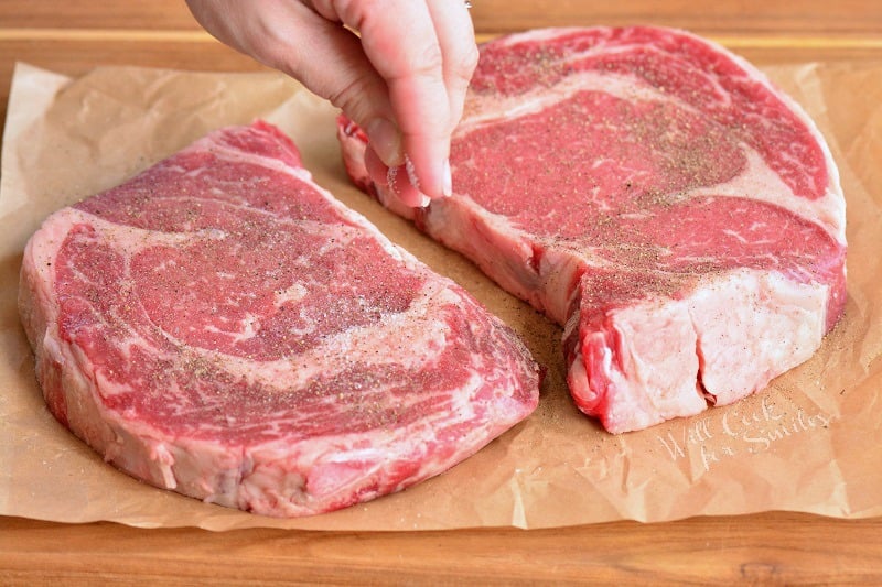 seasoning ribeye steaks with salt and pepper