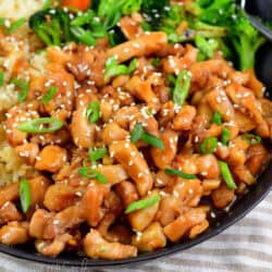 chicken teriyaki in a bowl topped with sesame seeds and green onion.