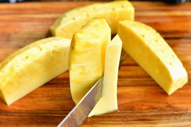 slicing the core off the pineapple quarter with other quarters around