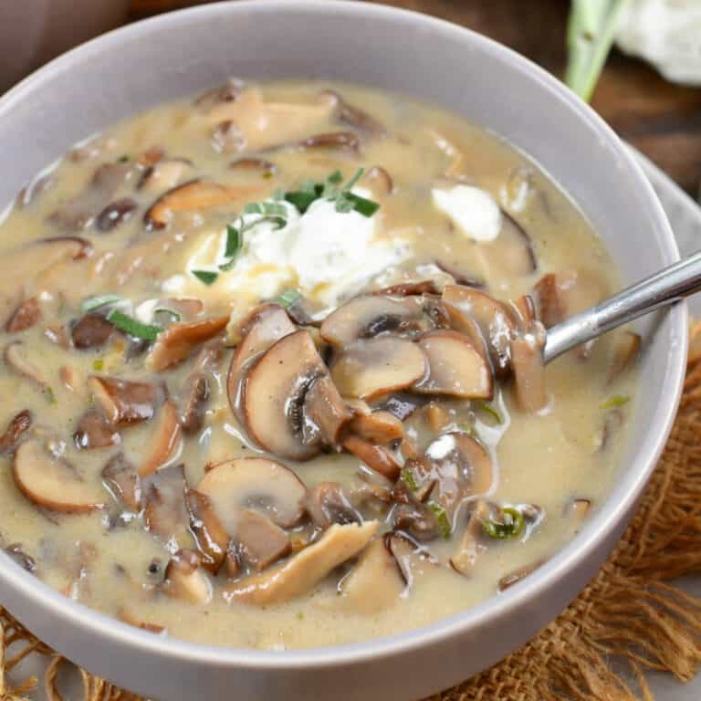 spooning out some creamy mushroom soup from the grey bowl.