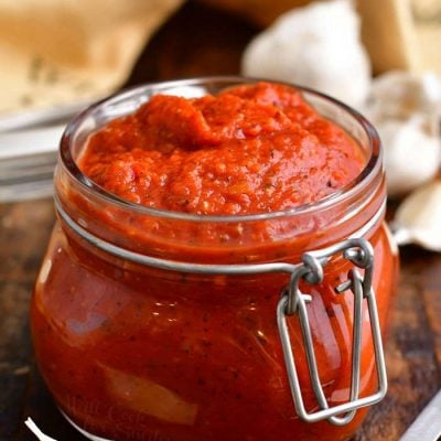 homemade pizza sauce with tomato paste in small glass jar on wooden counter top