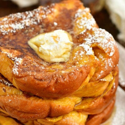 closeup top view of stack of French Toast topped with butter, syrup, and powdered sugar