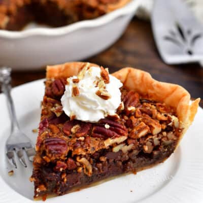 plated slice of chocolate pecan pie topped with whipped cream