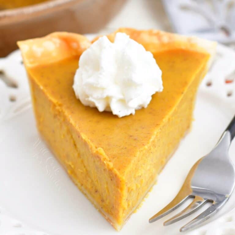 closeup of a front view of a slice of pumpkin pie with whipped cream