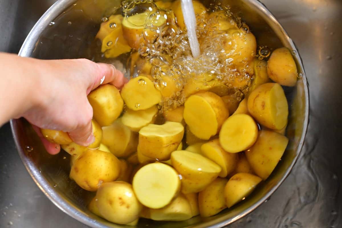 rinsing bowl of sliced potatoes under cold tap water