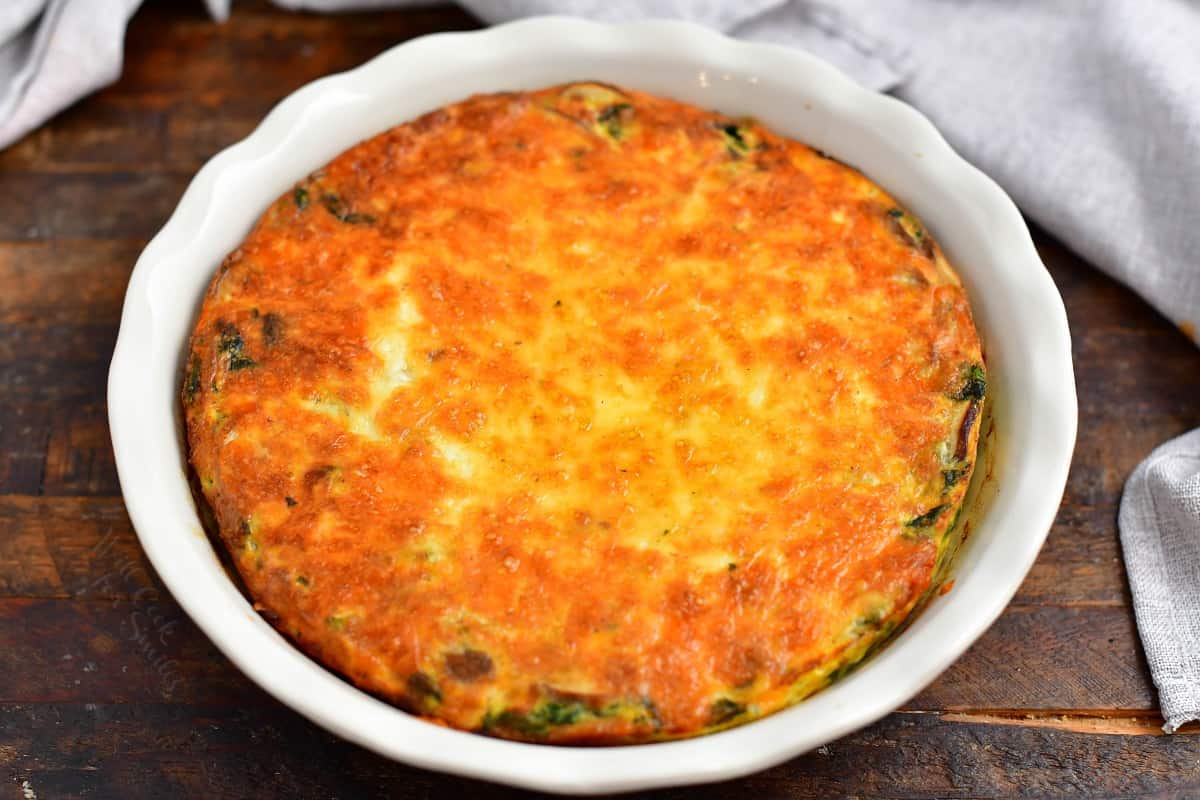 A baked quiche is cooling on a brown surface.