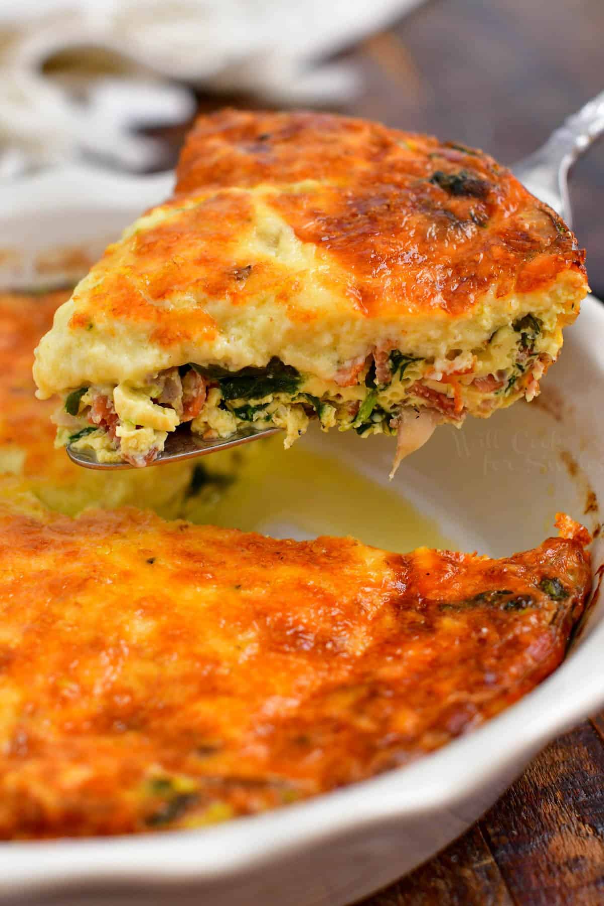 A slice of quiche is cut and lifted from the pan.