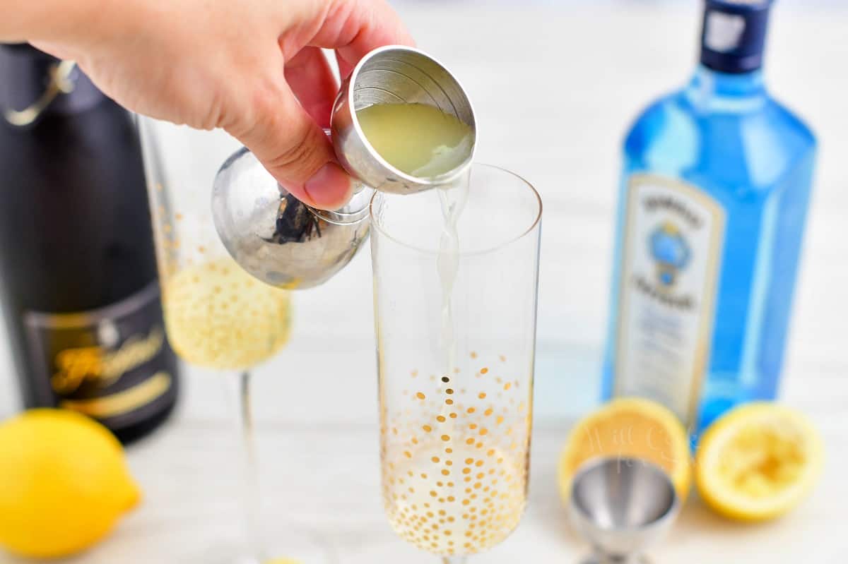 Lemon juice is poured into a sparkly glass for a French 75 recipe