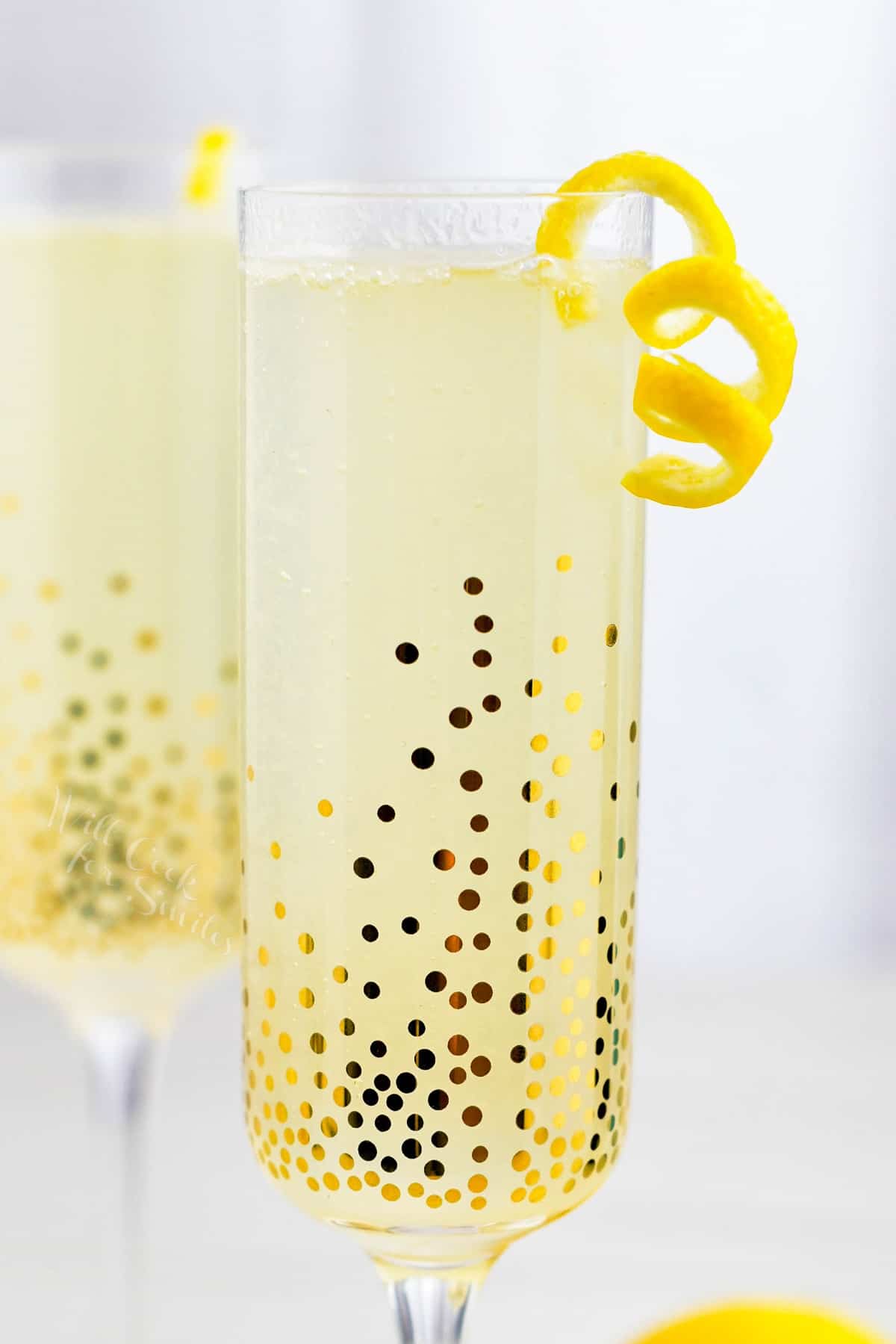 A French 75 is served in a sparkling, golden glass with a sliver of orange peel.