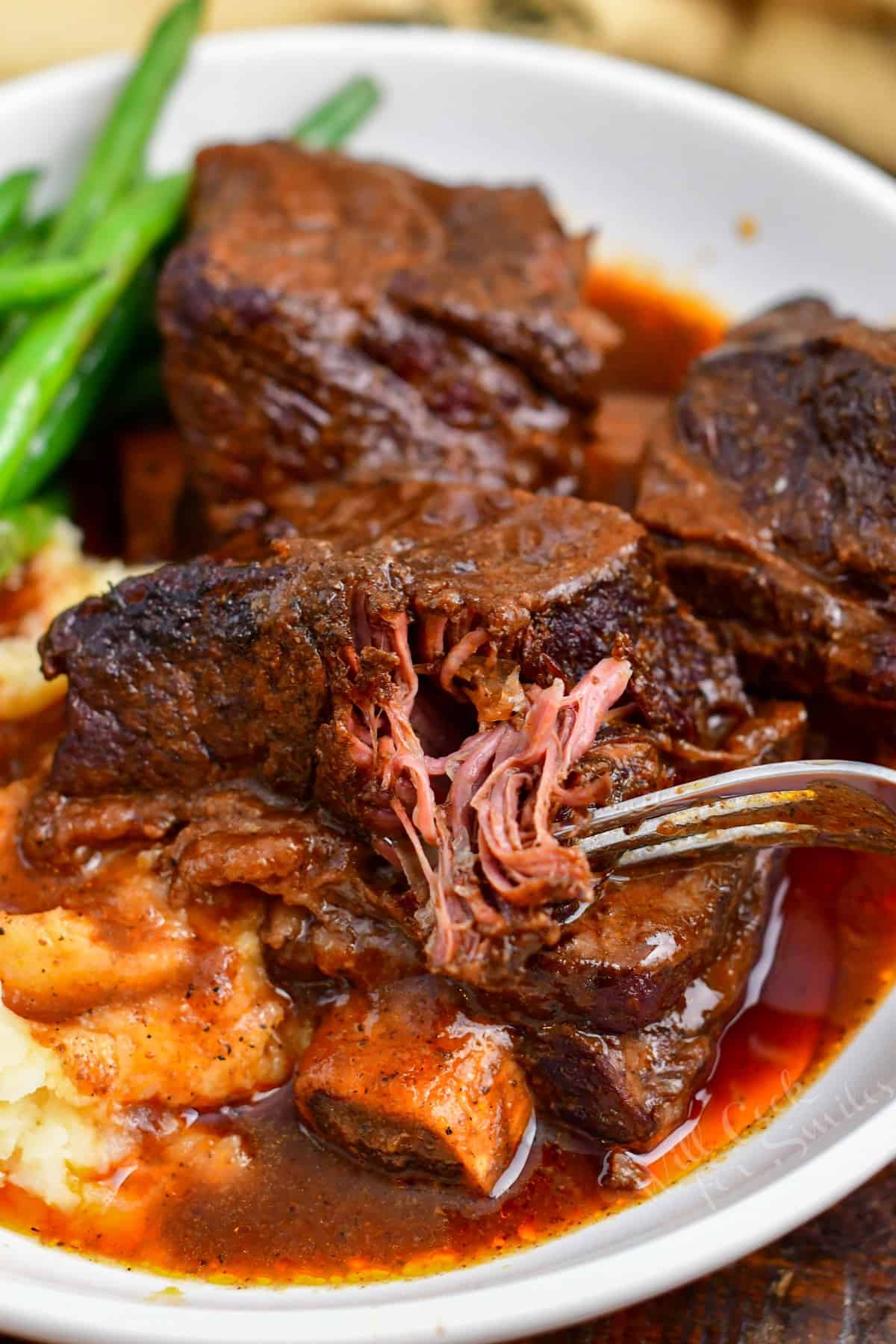 fork pulling tender meat from braised short ribs