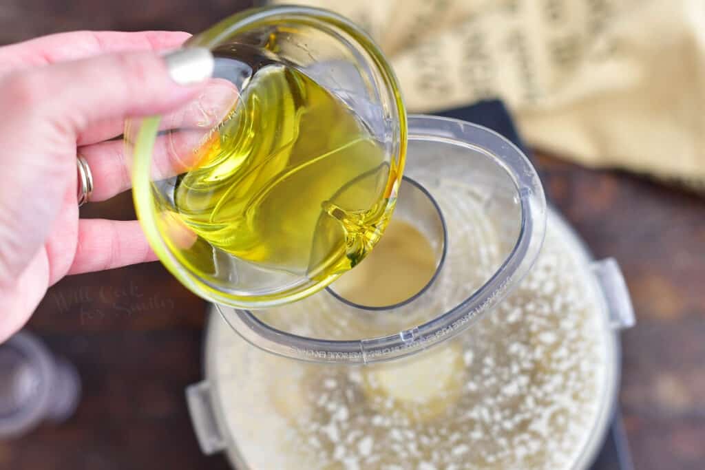 pouring olive oil into food processor for homemade salad dressing