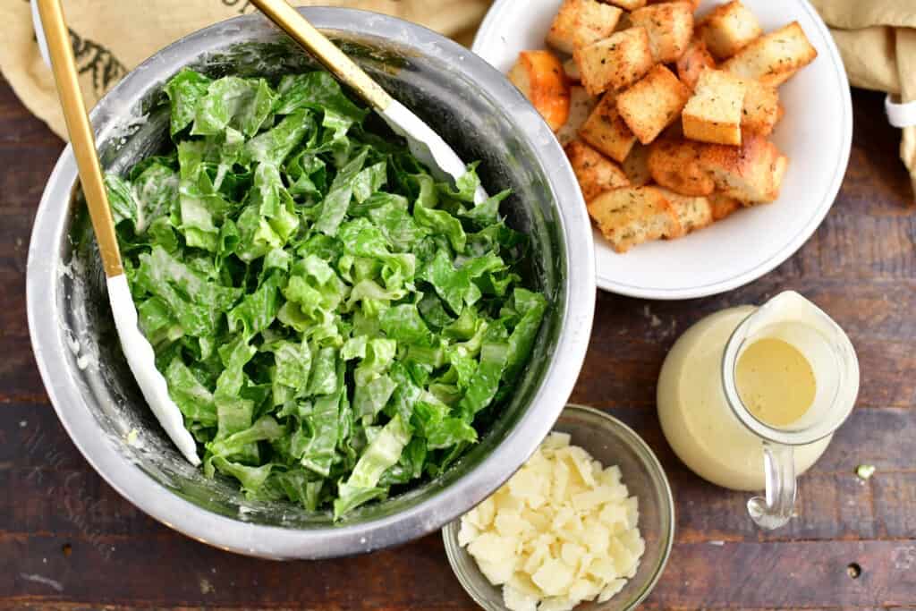 tossing a classic caesar salad with dressing in a bowl