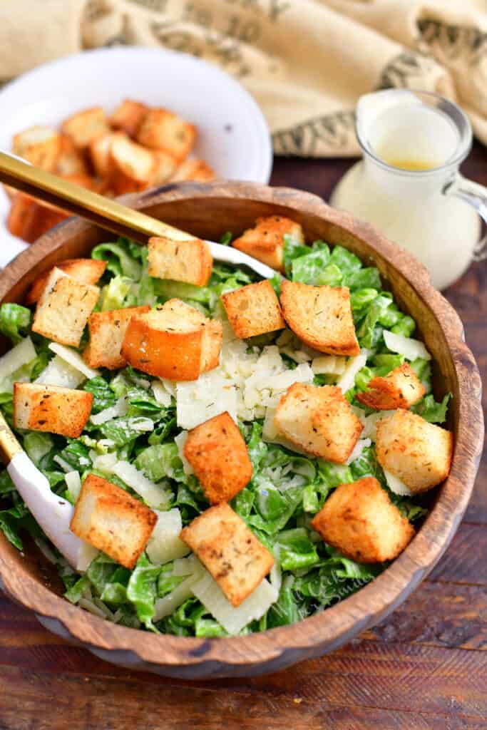 homemade caesar salad with garlic croutons and dressing in wooden bowl