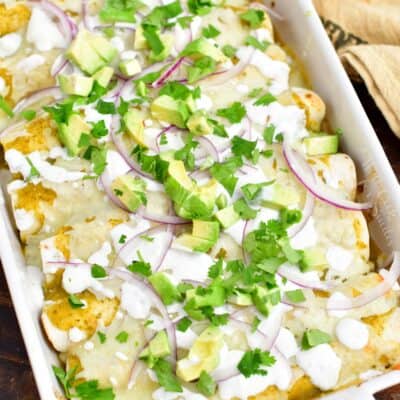 overhead: pan of green chicken enchiladas on a wooden surface with a towel