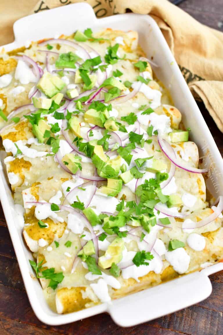 overhead: pan of green chicken enchiladas on a wooden surface with a towel