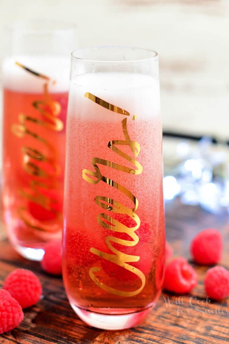 fresh raspberries scattered around two Kir Royale cocktails