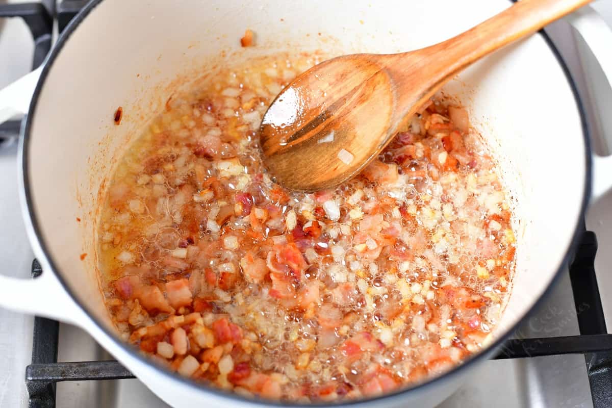 finely chopped bacon being crisped in a white dutch oven