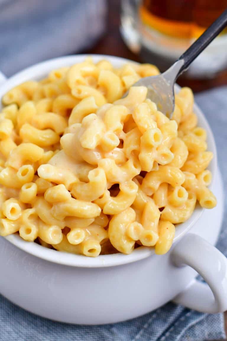 fork lifting creamy mac and cheese out of a soup bowl with handles