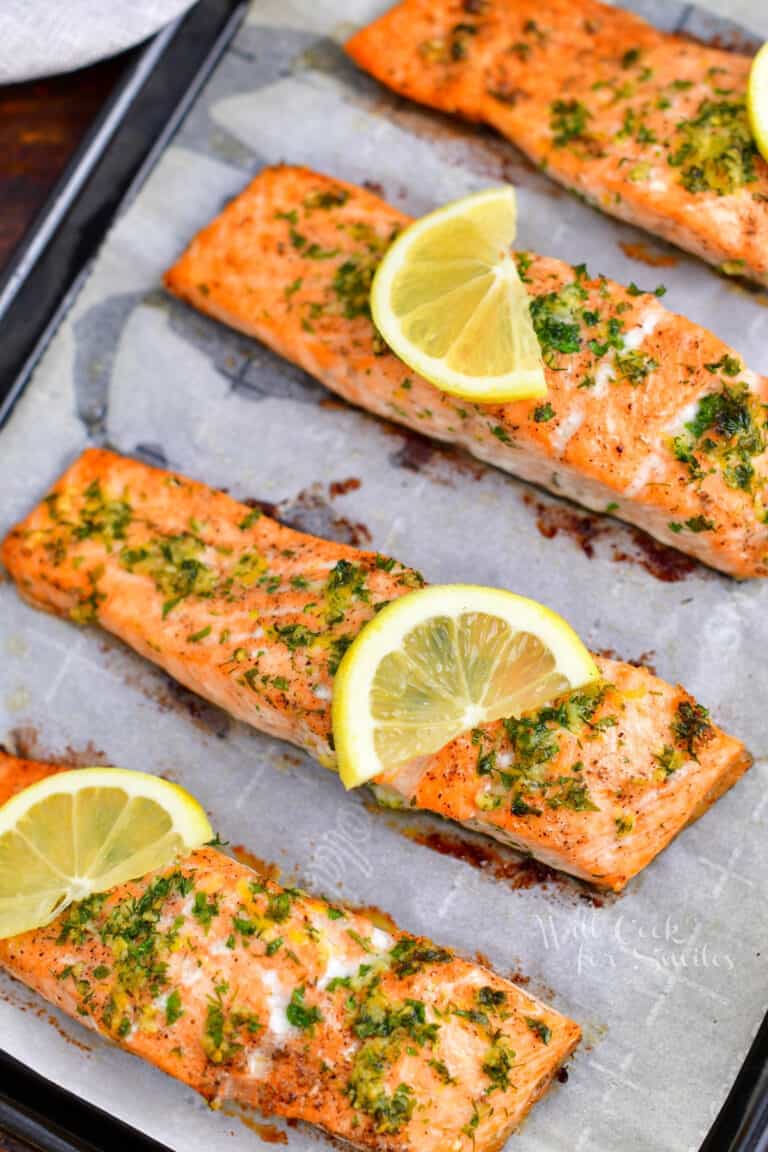 healthy baked salmon on baking sheet topped with slices of lemon