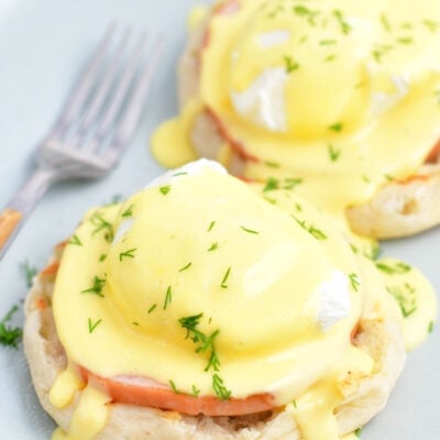 Two servings of Eggs Benedict are on a white plate.