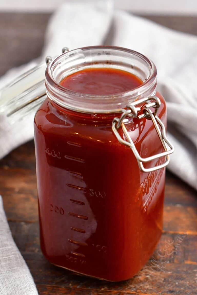 A jar of barbecue sauce is placed on a wooden surface.