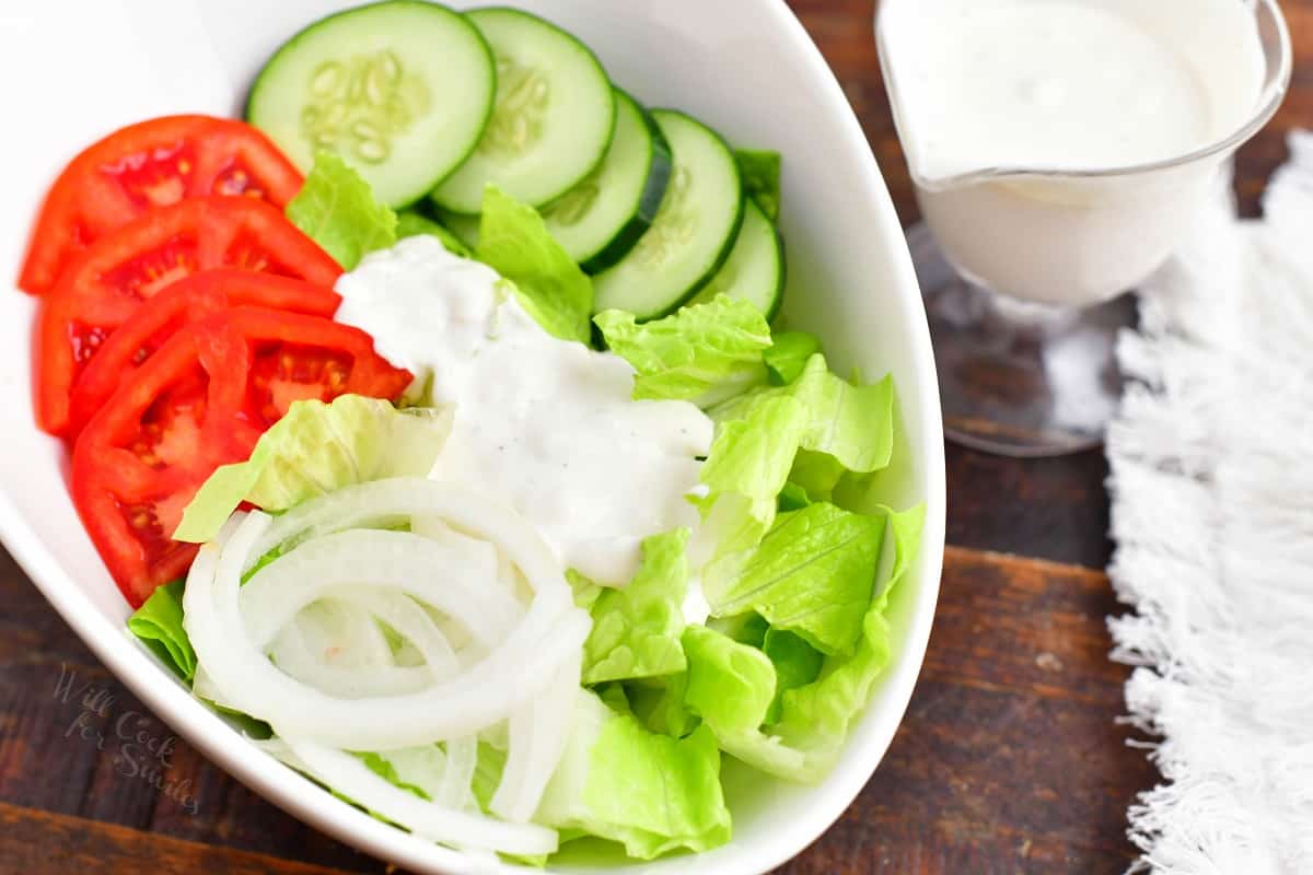 A small amount of blue cheese is drizzled on a chopped salad.
