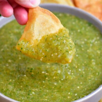 A chip is scooping a bite sized portion of salsa from the bowl.