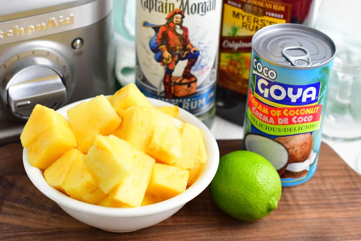 The ingredients for pina coladas are placed on a cutting board. 