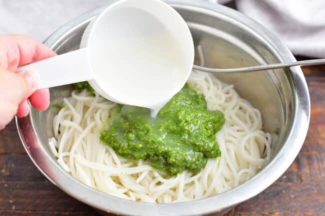 Pasta is topped with green pesto and cooking water. 