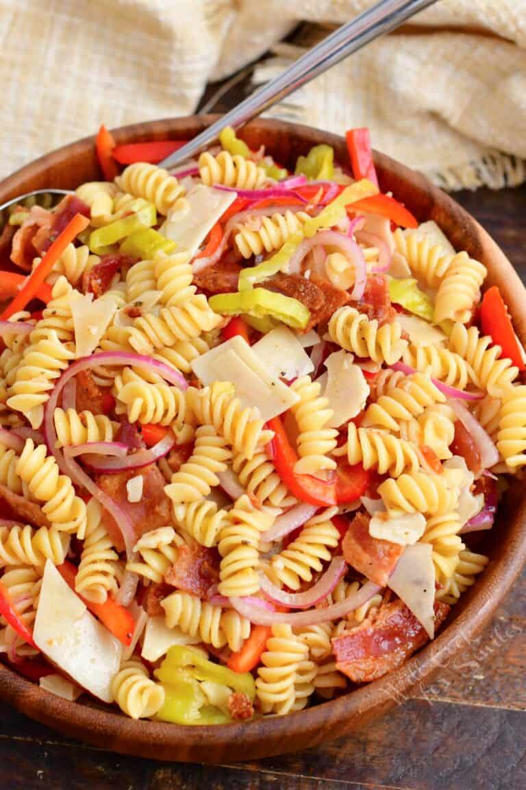 All of the ingredients for pasta salad have been thoroughly tossed in a large bowl.