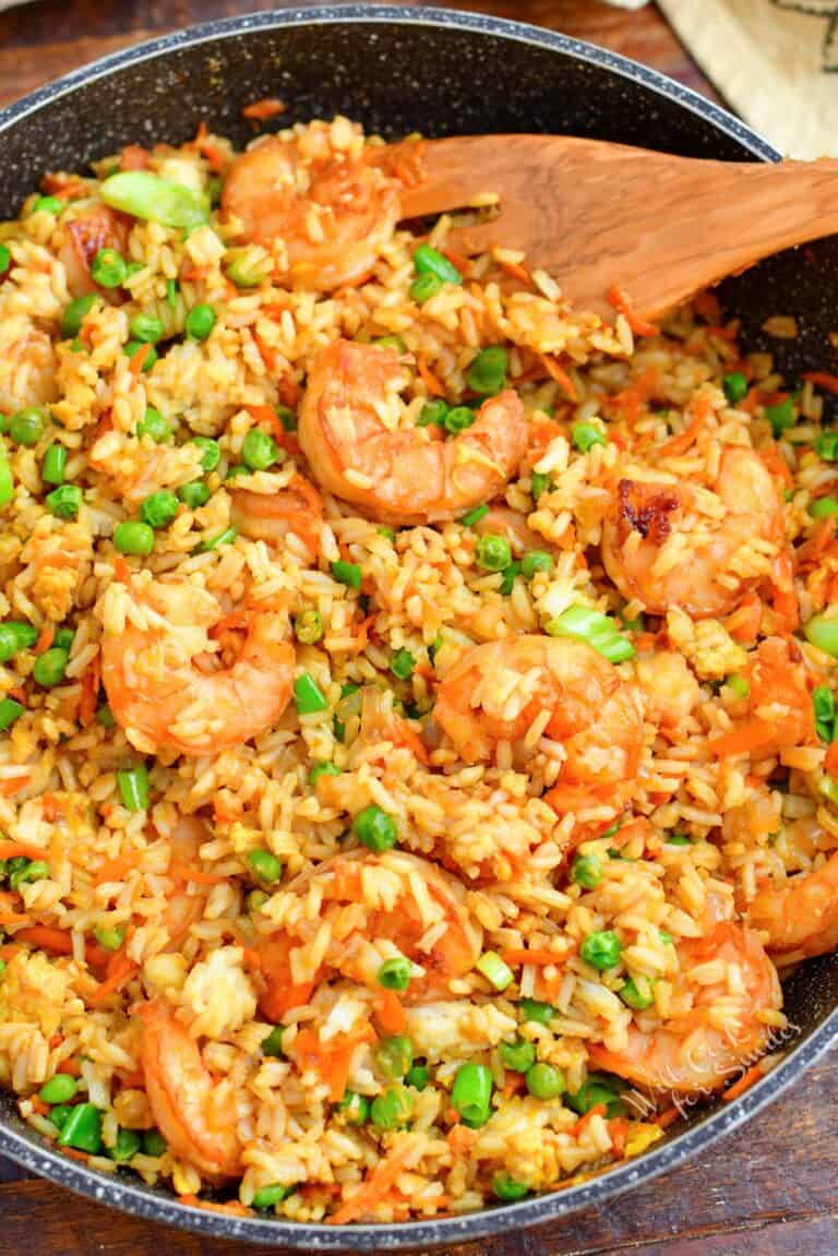 Shrimp fried rice has been cooked in a black skillet and is ready to serve.