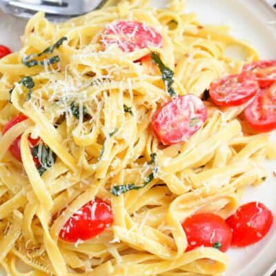 top view of creamy fettuccine on a plate with tomatoes basil and cheese