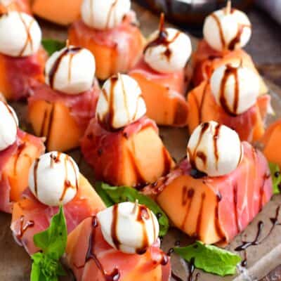 top view of melon wrapped in prosciutto with mozzarella ball and balsamic glaze