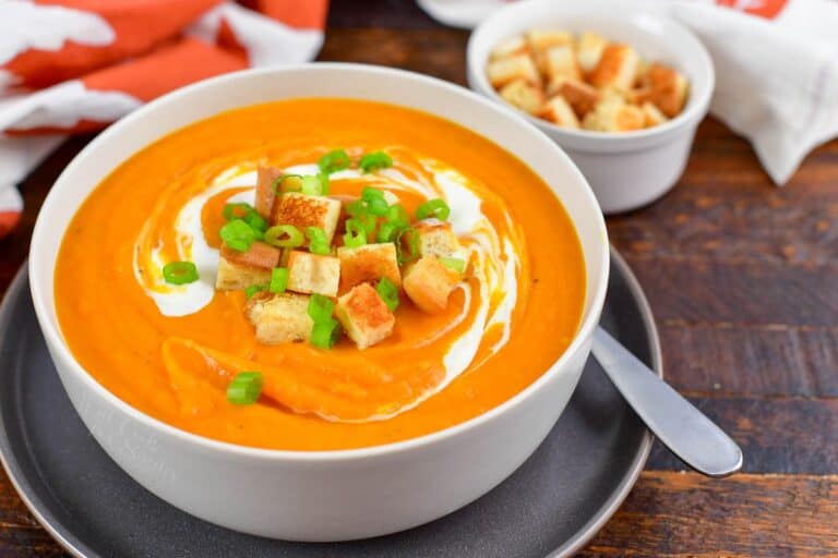 sweet potato soup in a bowl with croutons on top and next to the bowl