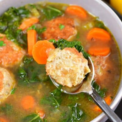 spoon with half of a chicken meatball over bowl of soup