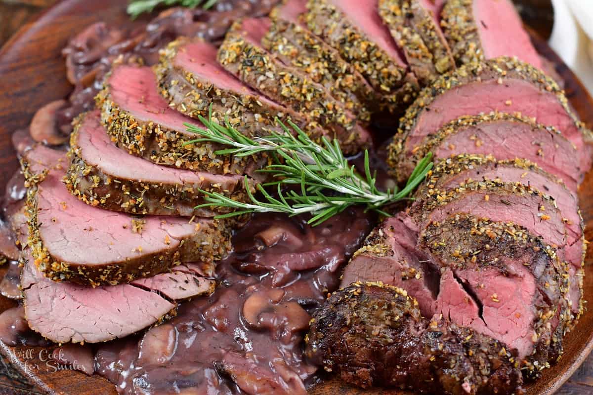 closeup of sliced beef tenderloin on top of mushroom sauce