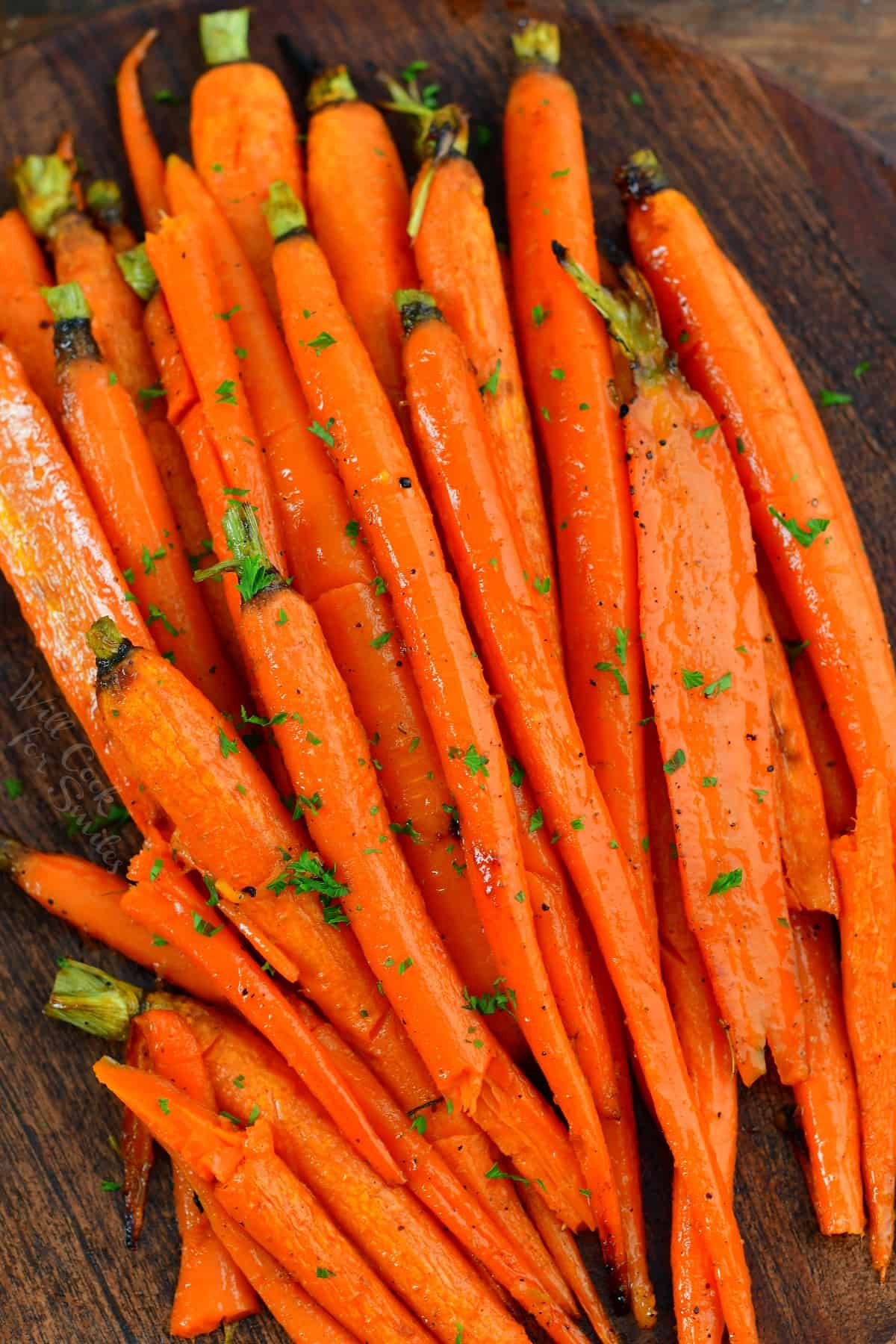 top view of glazed carrots on a wooden plate