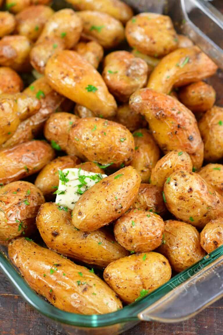 side view of roasted potatoes in a baking dish with butter and herbs