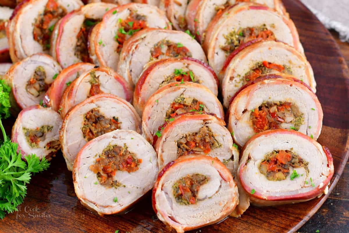 sliced stuffed pork tenderloin spread in a large wooden platter